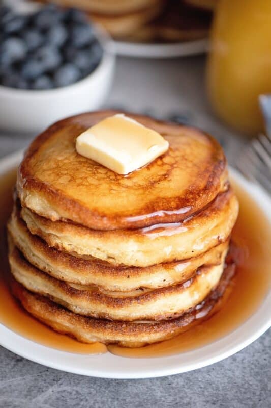 Stack of pancakes with a lot of butter and syrup.