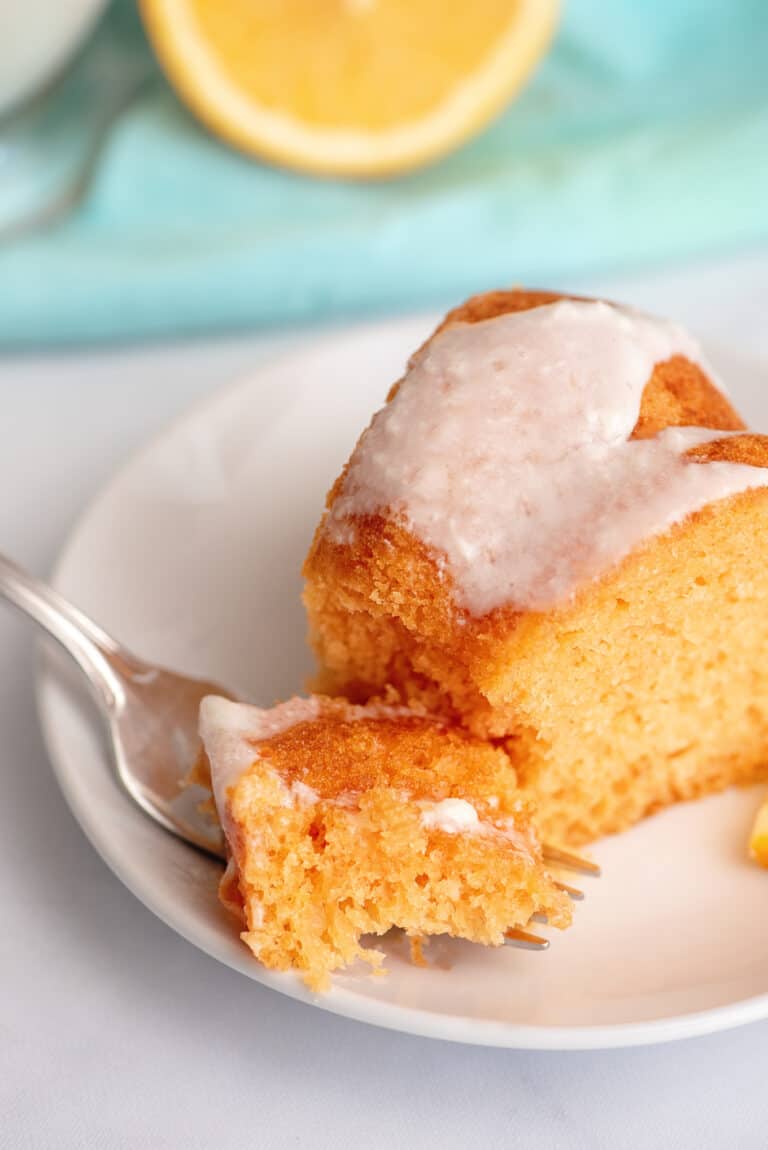 Fork breaking off a piece of orange cake.