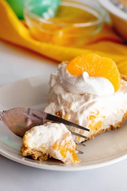 Fork breaking off a piece of mandarin orange pie.