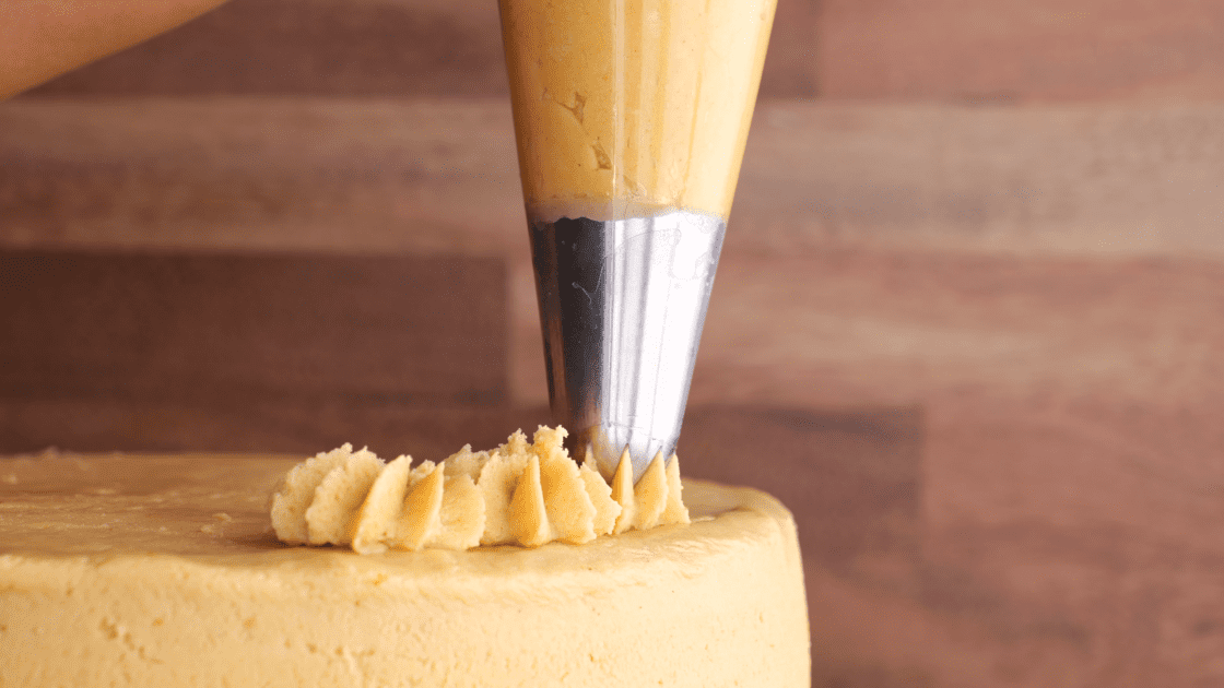 Piping peanut butter frosting onto cake.