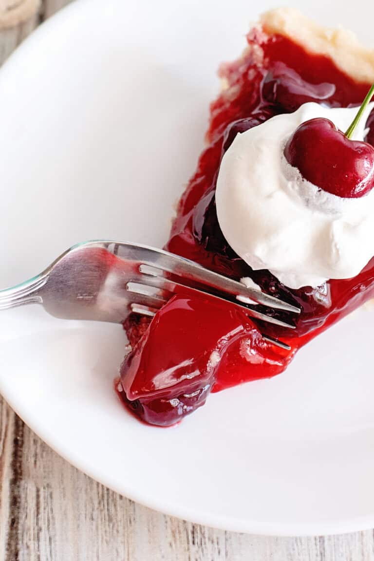 Fork breaking into a slice of cherry jello pie.