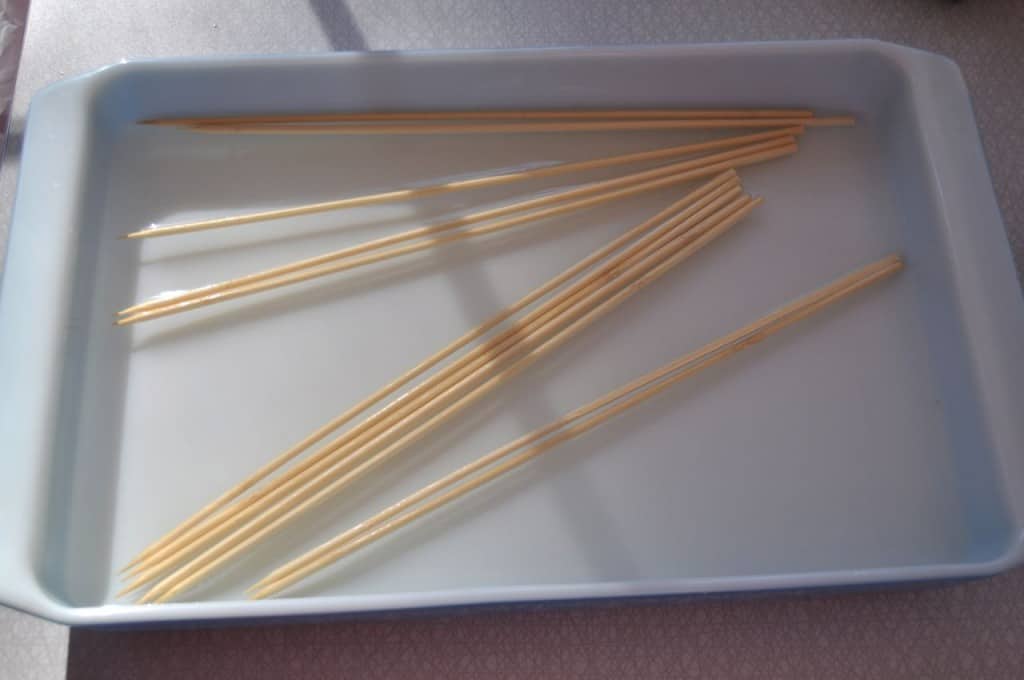 Soaking wooden skewers in baking dish filled with water.
