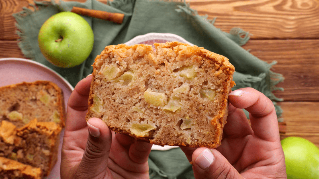 Hands holding a slice of apple bread.