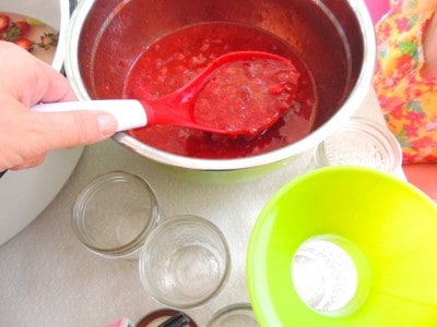 Scooping jam into jars.