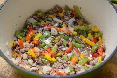 Add onion and peppers to beef.