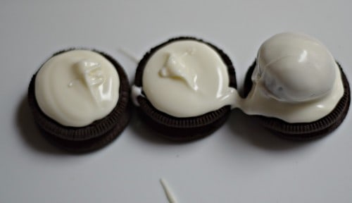 Add drop of chocolate to center of Oreo cookie and place coated ball on top.