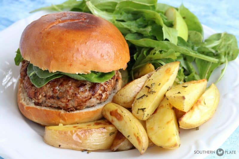 Ground pork burgers on plate with greens and fries.