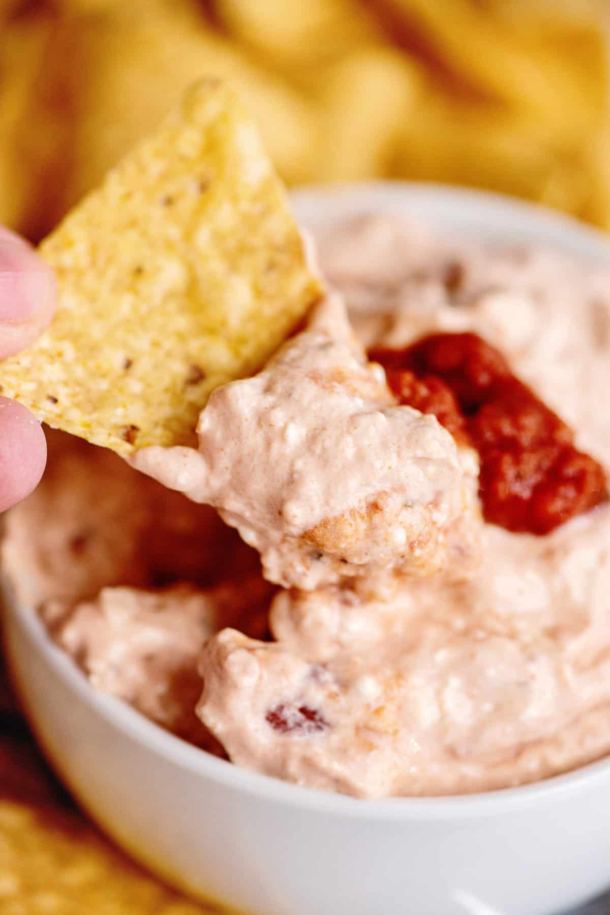 A scoop of cream cheese salsa dip on a tortilla chip.