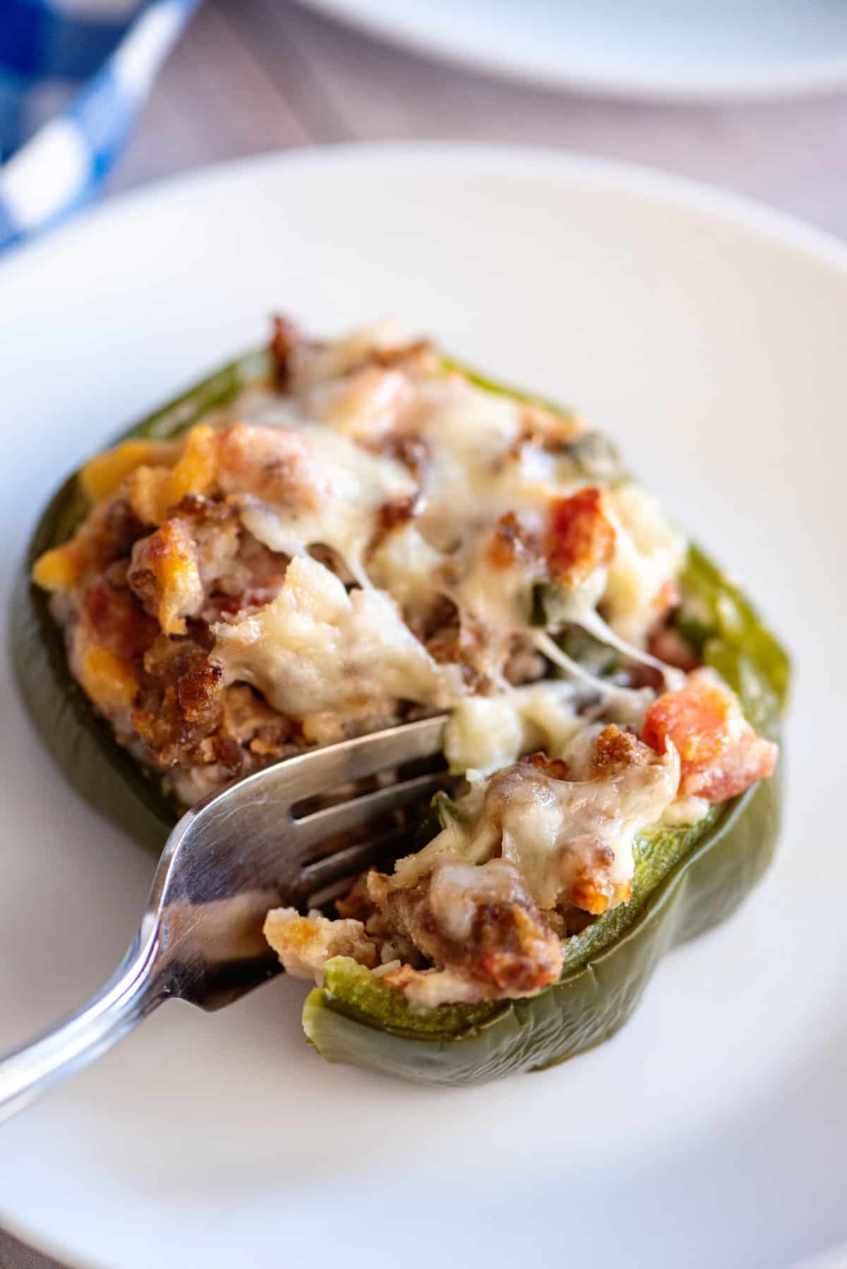 Fork breaking off a piece of sausage stuffed pepper.