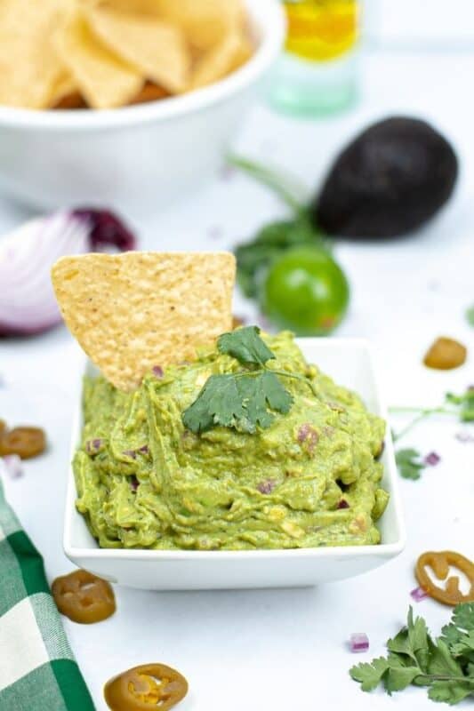 square bowl of guacamole on table 