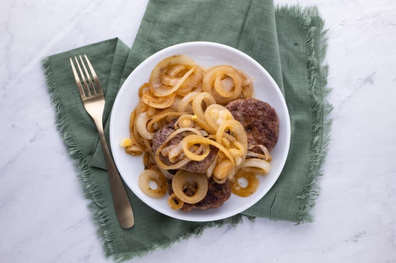 Hamburger steaks on plate with fried onions.