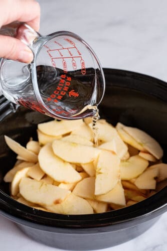 Pouring water over apples in crockpot.