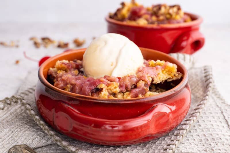 Cherry pineapple dump cake in bowl with ice cream.