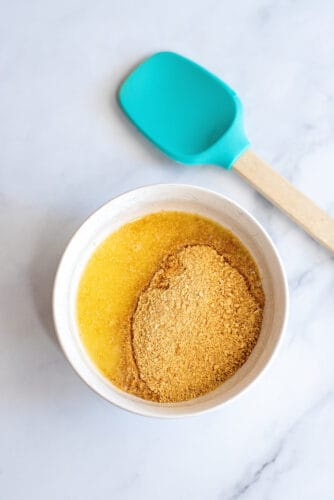 Graham cracker crumbs and melted butter in bowl.