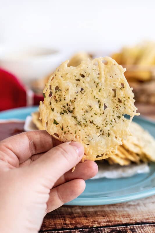 Hand holding up a parmesan crisp.