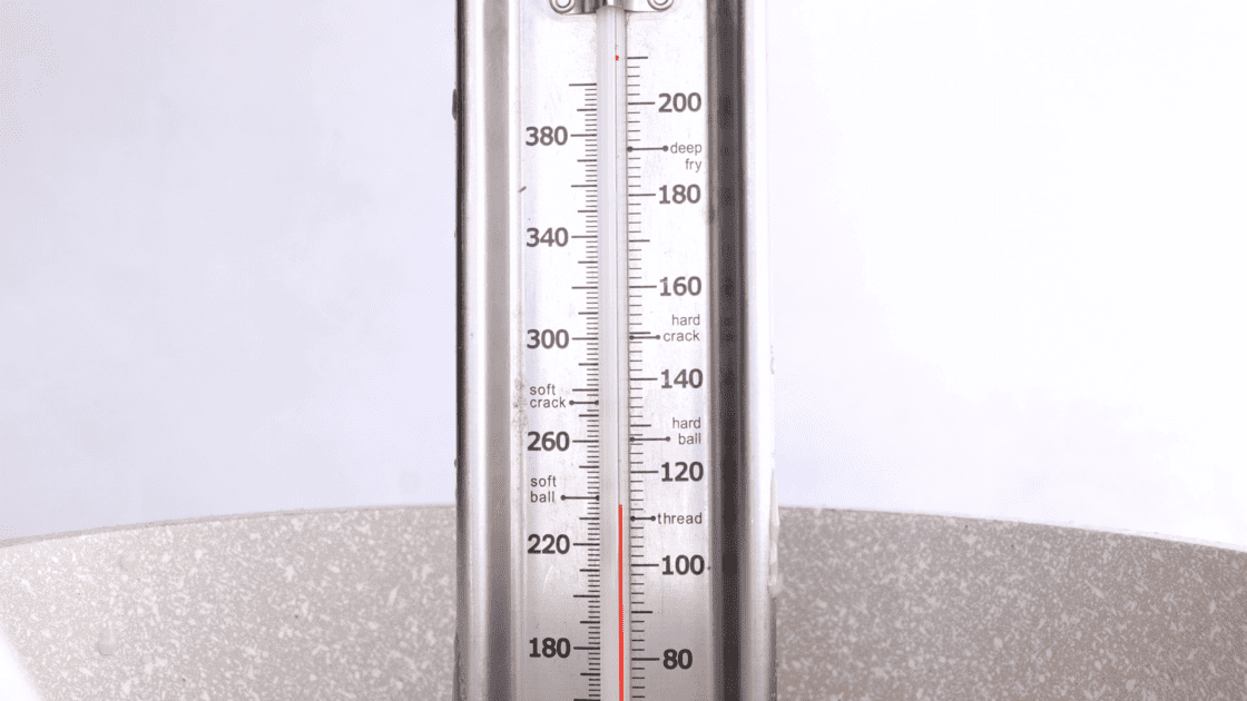 Candy thermometer in saucepot at the soft ball stage.