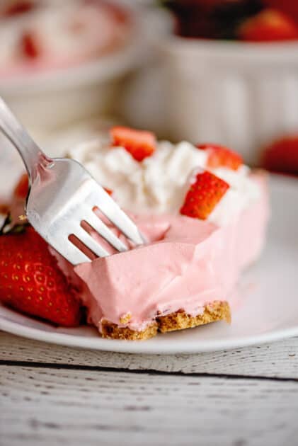 Fork digging into a piece of strawberry jello pie.