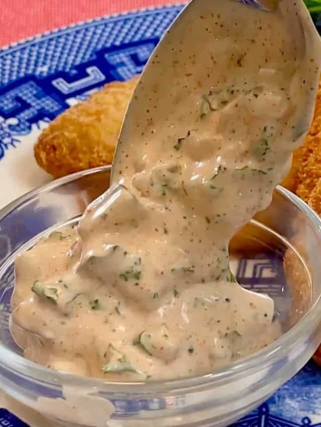 Spoonful of homemade tartar sauce with fish fillets.