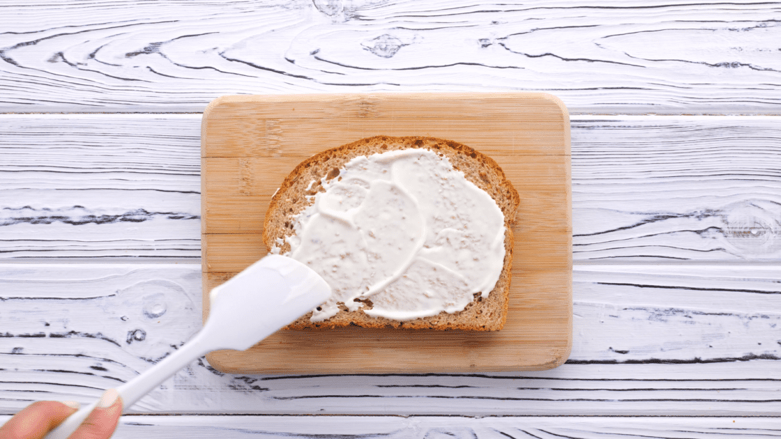 Spread mayo on slice of bread.