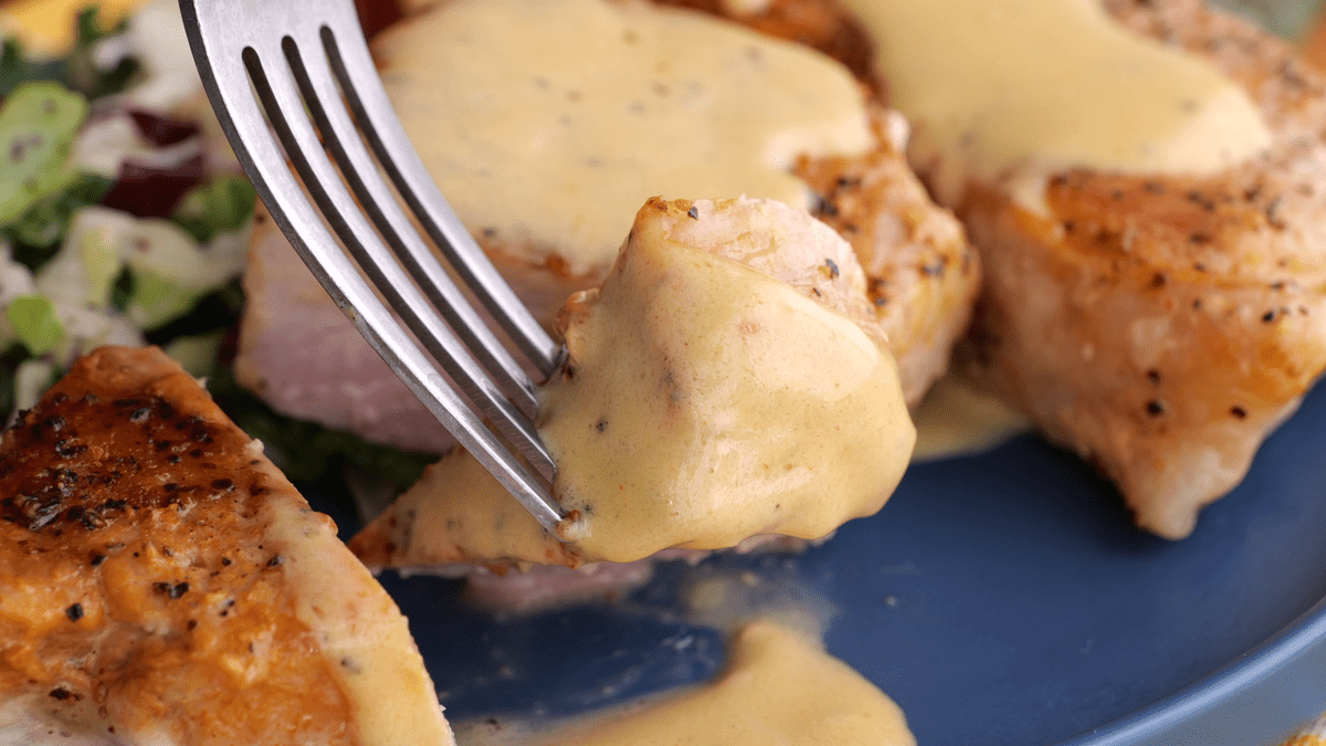 Close-up of pan-seared pork chop with velvet cream sauce.