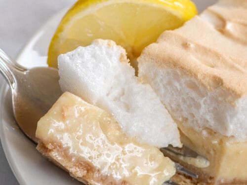 Bite of lemon meringue pie with condensed milk on plate.