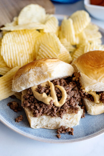 Loose meat sandwiches on plate with potato chips.