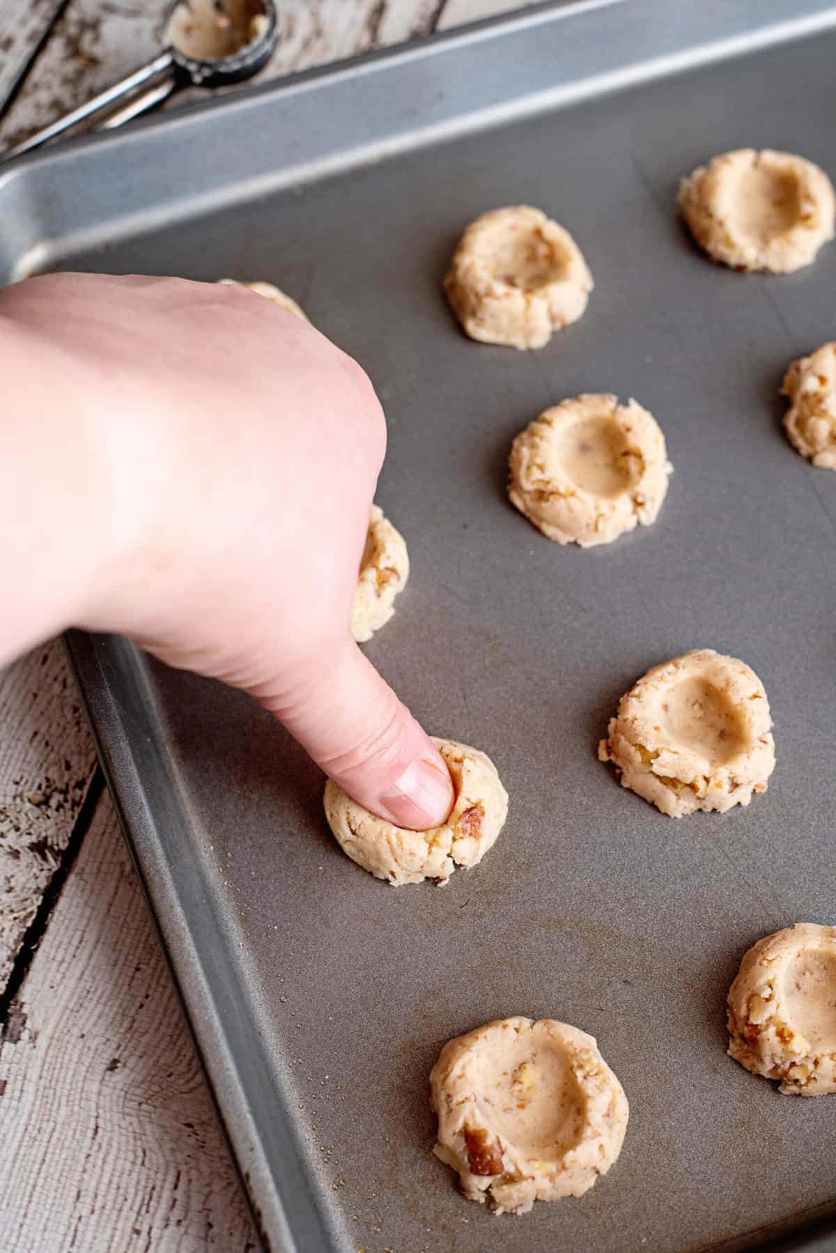 dip thumb into flour and make a print in each pecan thumbprint cookie