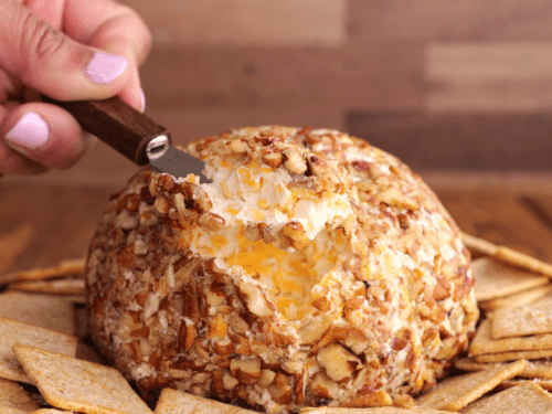 A knife holding a serving of cheese ball.