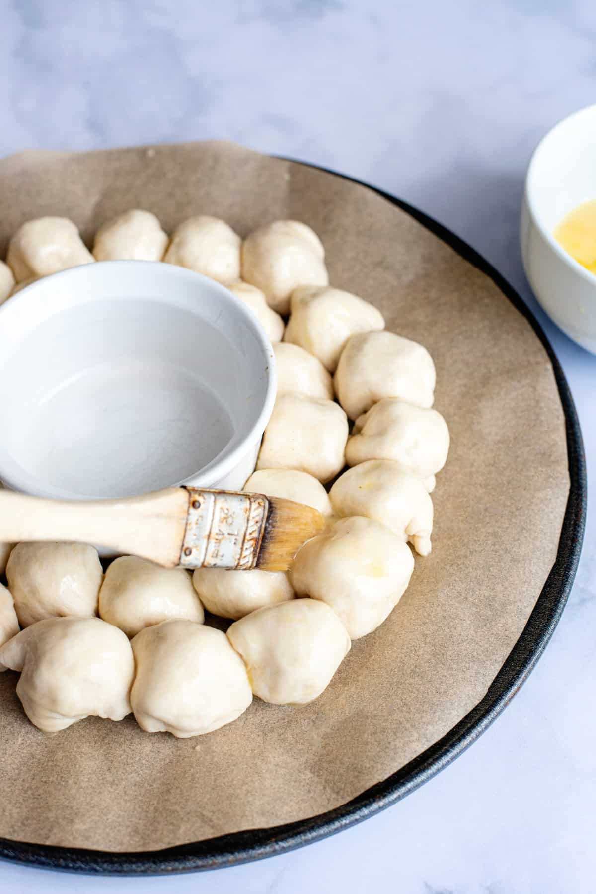 brush dough balls with egg wash for Cheesy Pull Apart Bread Christmas Wreath