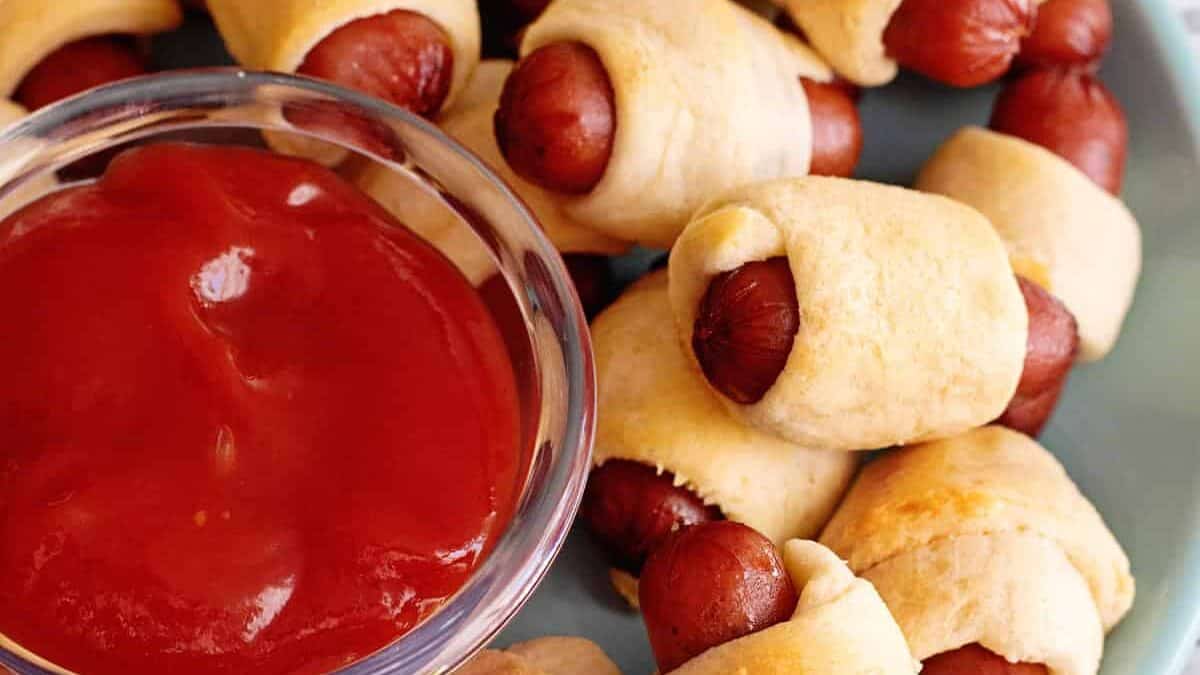 Plate of little smokies pigs in a blanket with ketchup.