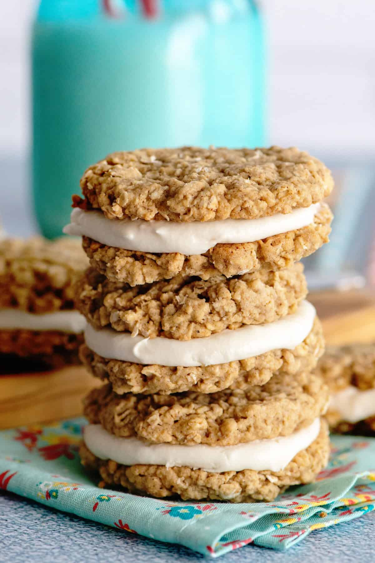 Three oatmeal cream pies stacked on a patterned turquoise napkin.