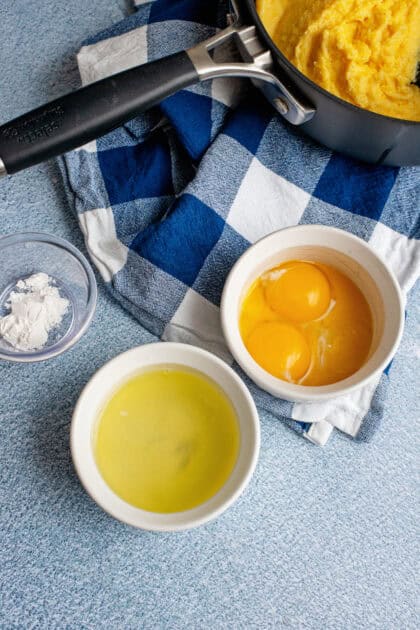 Egg yolks in a white bowl next to egg whites in a white bowl.